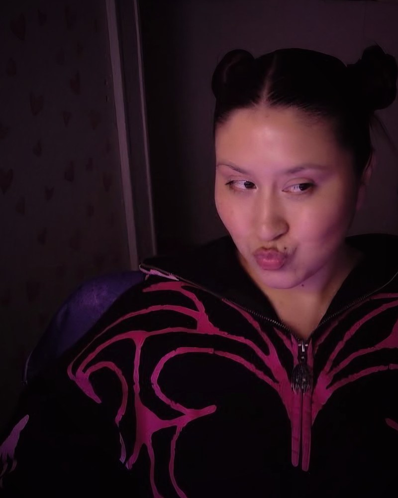 Savvy in a black and pink zip hoodie with space buns